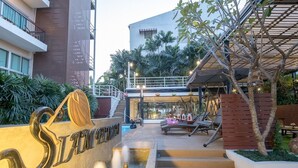 A hotel entrance with a sign, outdoor seating, and a pool area. - Siam Piman Hotel (Bangkok)