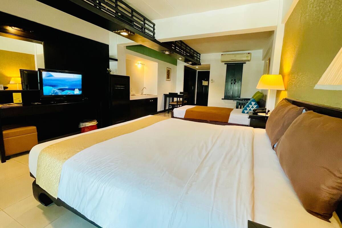 Een hotelkamer met een groot bed, een televisie, een bureau met een computer en een badkamer.