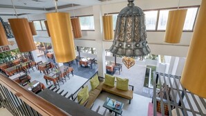 A spacious indoor area with multiple seating arrangements, including tables and sofas, and hanging pendant lights. - Siam Piman Hotel (Bangkok)