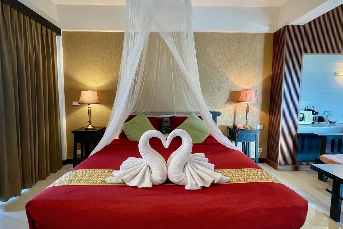 Een hotelkamer met een bed, een hemelbed, twee lampen en een ontbijhoek.