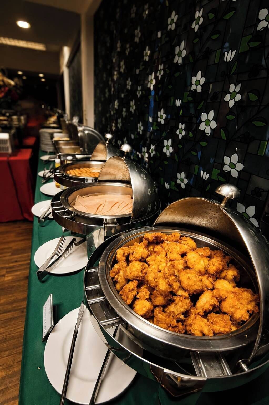 A buffet setup with various food items and serving utensils.