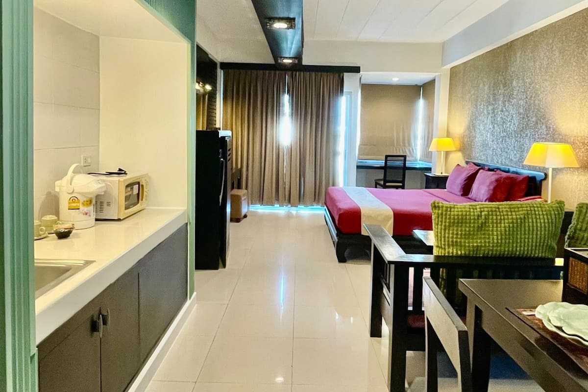 Een hotelkamer met een kitchenette, een bed, een bureau en een eethoek.