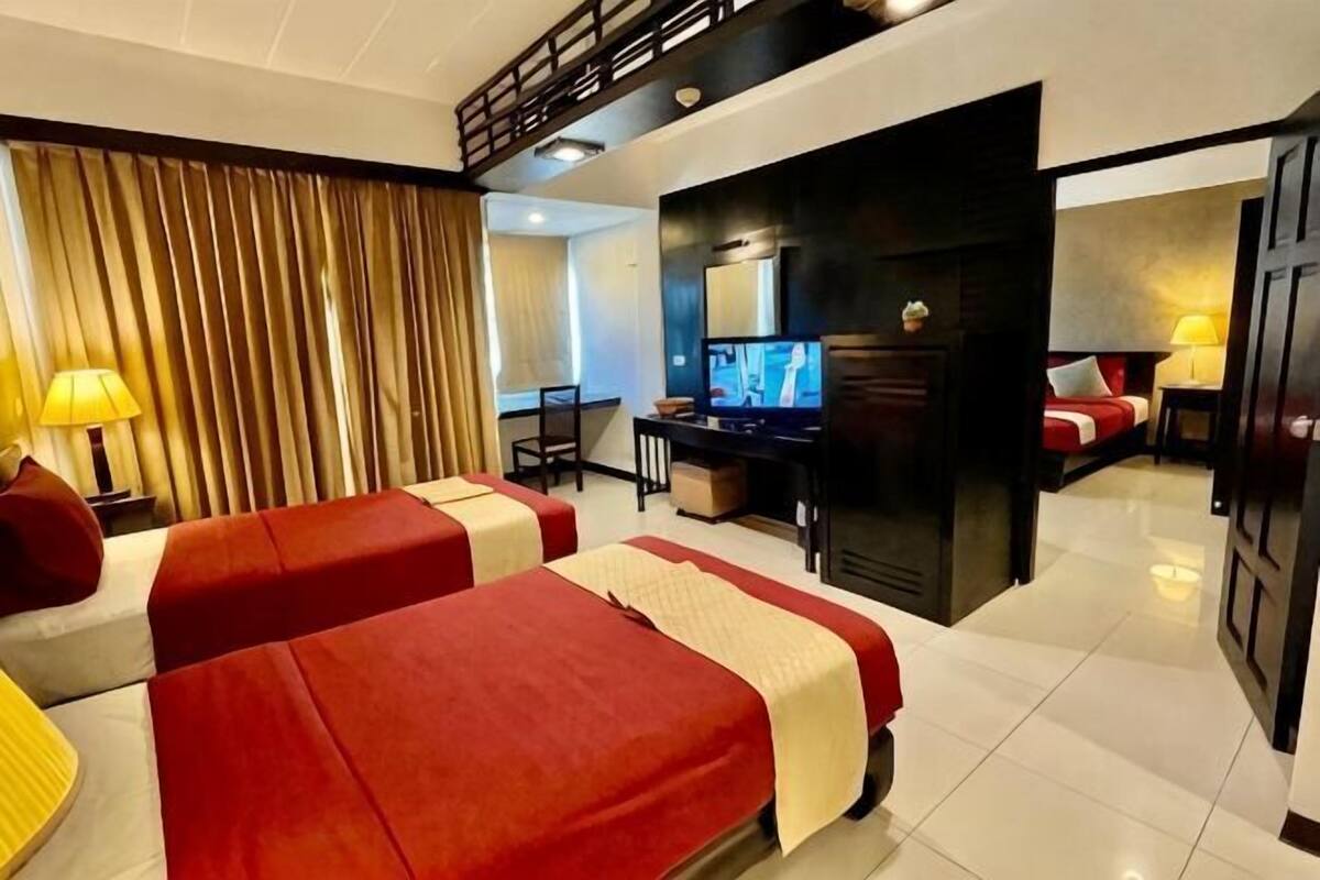 Een hotelkamer met twee bedden, een bureau, een televisie en een aparte zithoek met een stoel en een tafel.