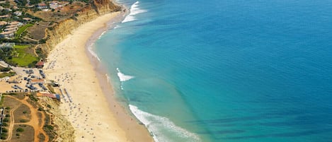 Di pantai, pasir putih, kursi berjemur, dan payung pantai