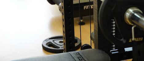 A weight bench with a barbell and weight plates.