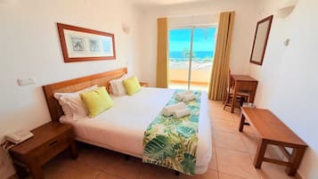 Una habitación de hotel con una cama, una mesita de noche con teléfono, un escritorio y una silla.
