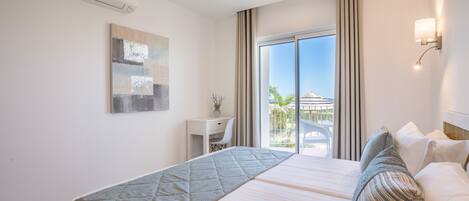 A hotel room with a large bed, a desk, and a view of the outdoors.