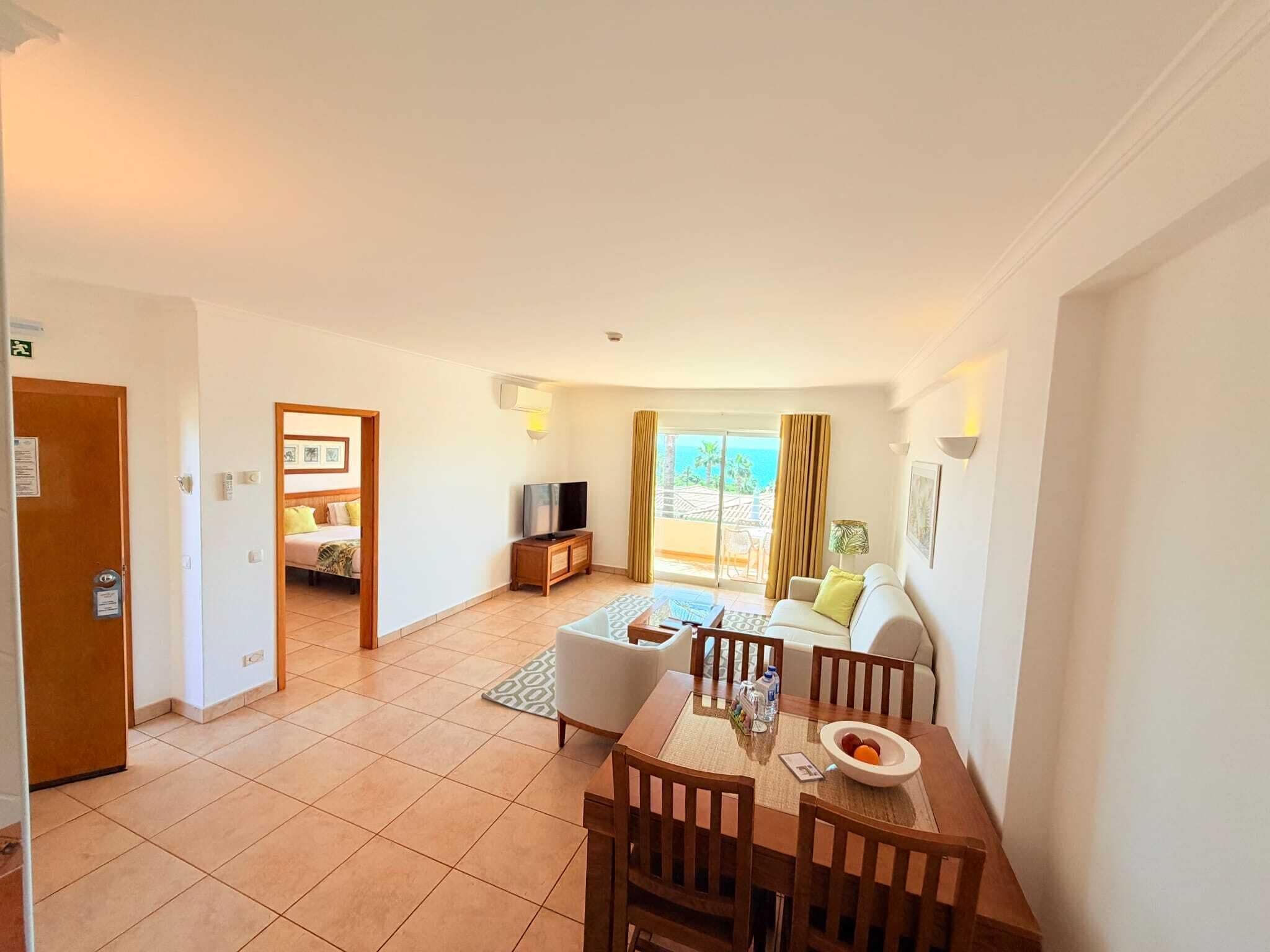 Une chambre d’hôtel avec un coin repas, un canapé, une télévision et un balcon avec vue.