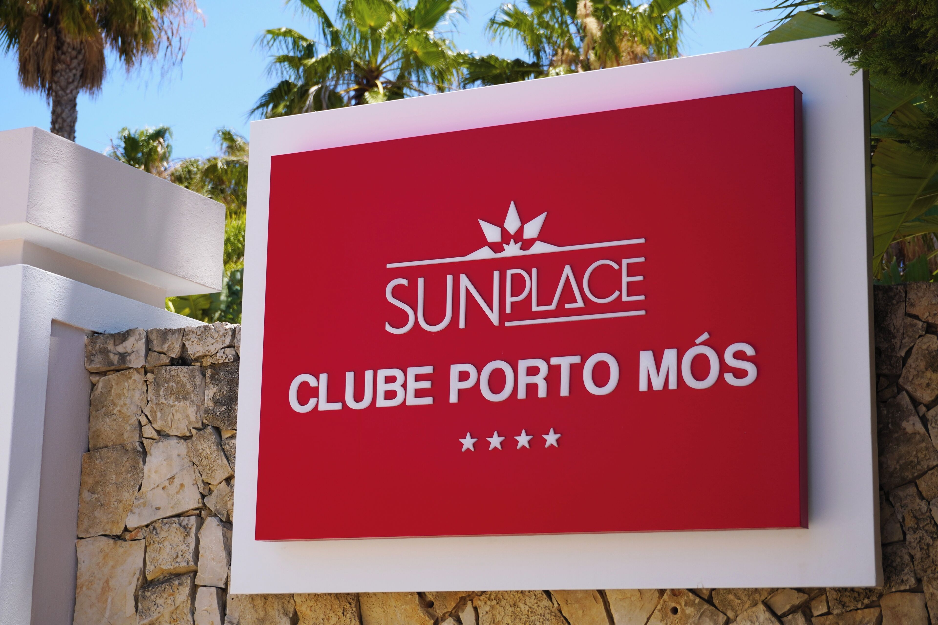 A red sign with white text for 'SUNPLACE CLUB PORTO MÓS' and a star rating of four stars.