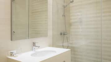 Une salle de bain moderne avec un lavabo blanc, un miroir et une douche en verre.