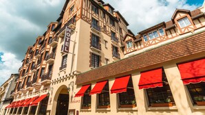 Een hotel met meerdere verdiepingen, in traditionele Europese architectuur, met een opvallend bord voor 'Hotel de Lettonie' en rode luifels boven de ramen.
