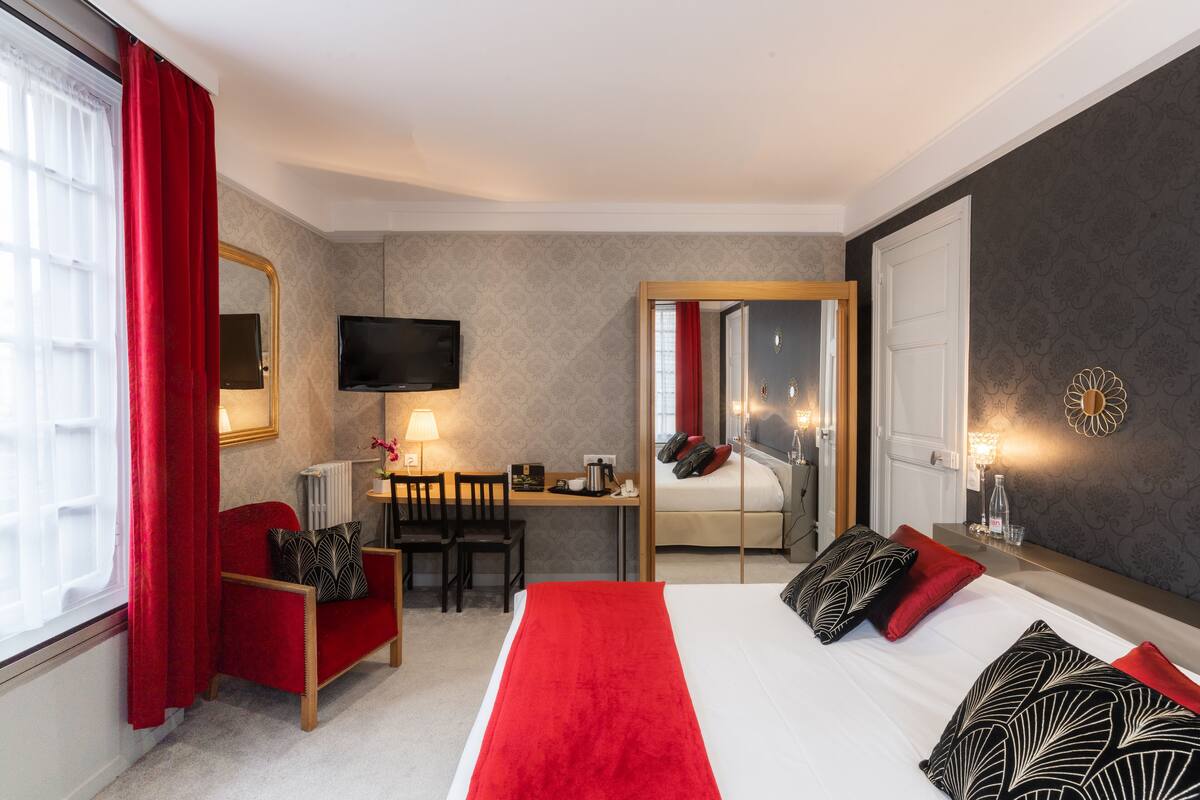 Een hotelkamer met een bed, een bureau, een stoel, een televisie en een spiegel.