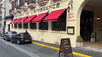 A restaurant with red awnings and a sign reading 'Chef Alain's Restaurant.'