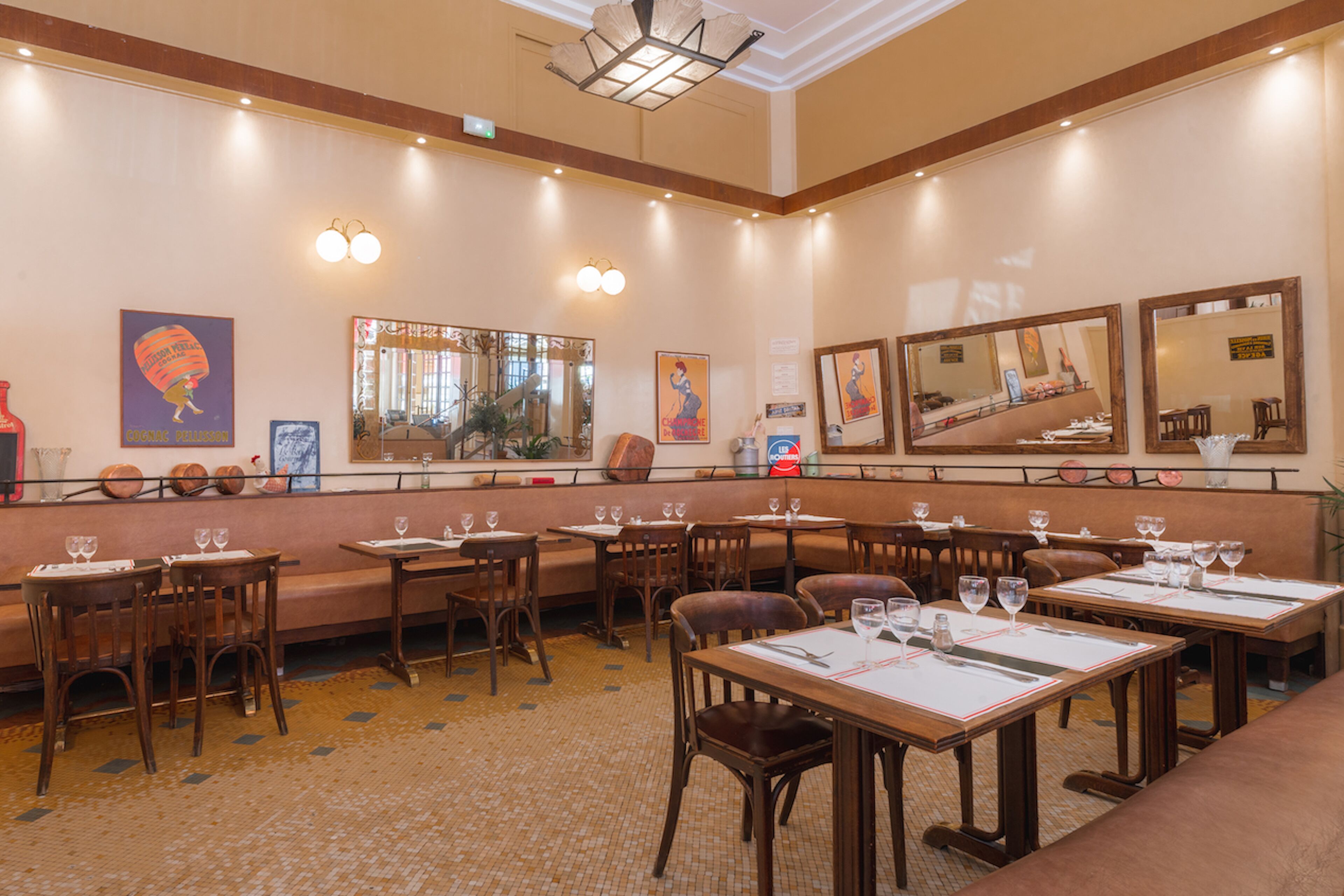 Een restaurant met meerdere tafels en stoelen, een bar en een grote spiegel aan de muur.