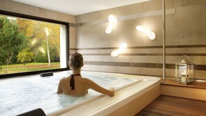 Ein Spa-Raum mit großem Fenster, Whirlpool und Holzboden.