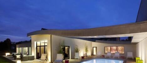 A modern outdoor pool area with lounge chairs and a covered seating area.