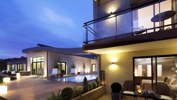 Ein modernes Hotel mit Pool, Außenbereich und einem Balkon mit Tisch und Stühlen.