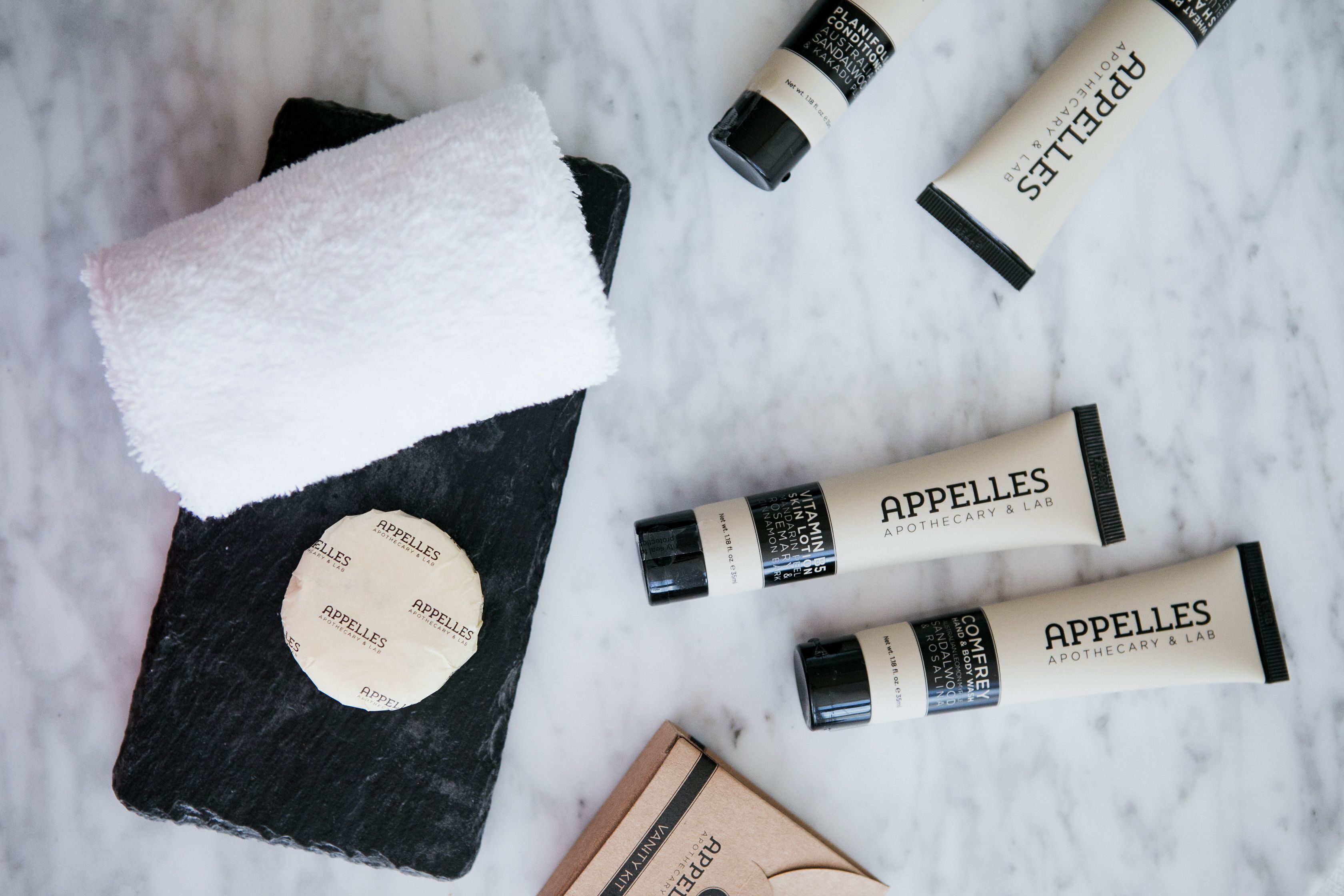 A marble surface with skincare products, a black book, and a white towel.
