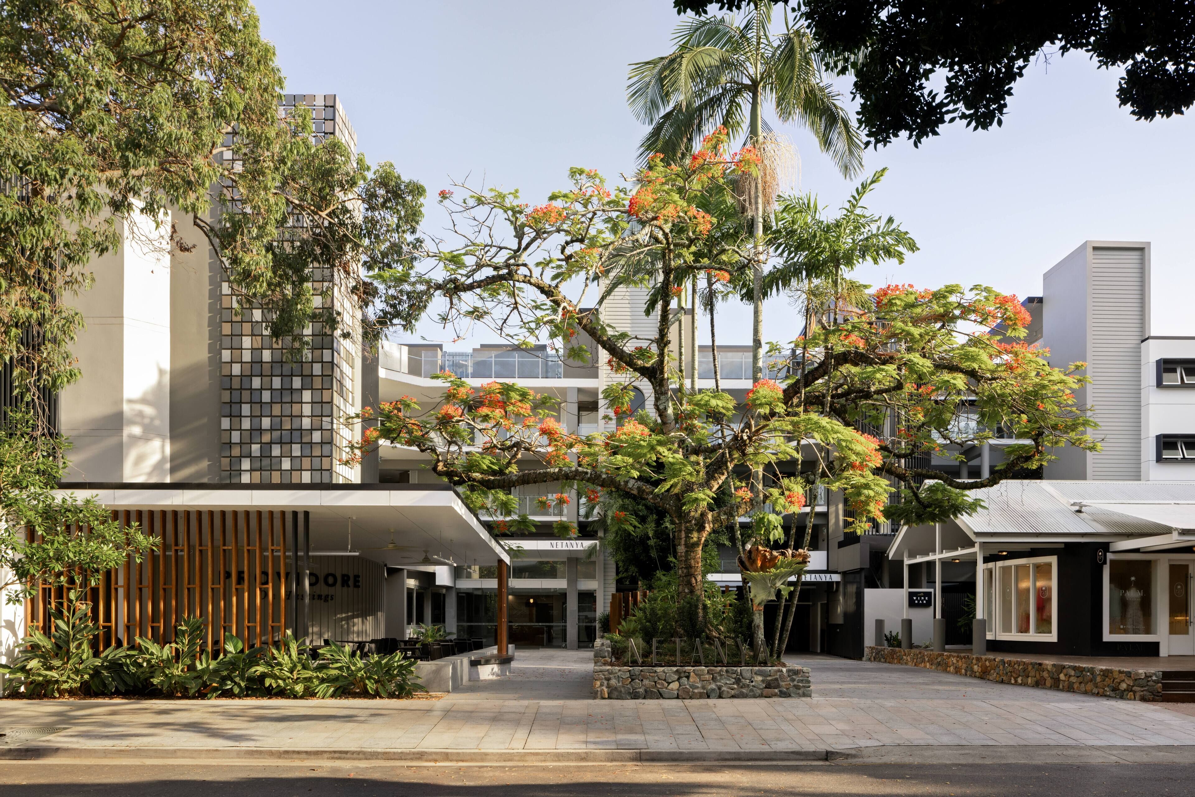 Un hotel moderno con un patio central, mobiliario exterior y una combinación de arquitectura contemporánea y tradicional.
