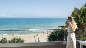 A balcony with a view of a beach, palm trees, and the ocean. - Netanya Noosa Beachfront Resort (Noosa Heads)