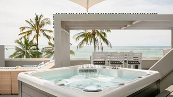 A hot tub with a view of the ocean and palm trees.