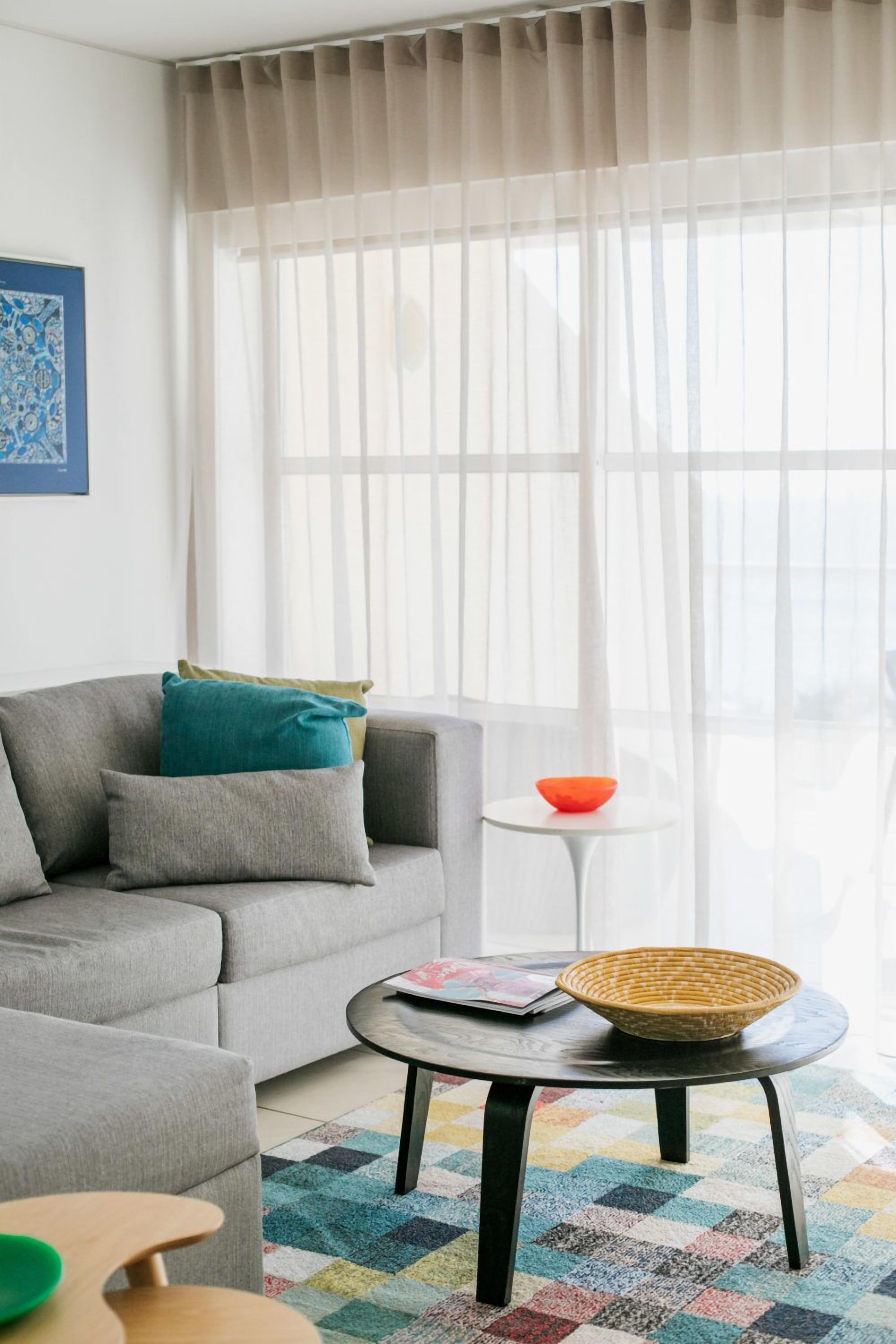 Un salon avec un canapé gris, une table basse ronde et un tapis coloré.