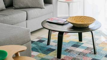 Un salon avec un canapé gris, une table basse ronde et un tapis coloré.