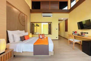 Una habitación de hotel con cama, escritorio, televisor y aire acondicionado.
