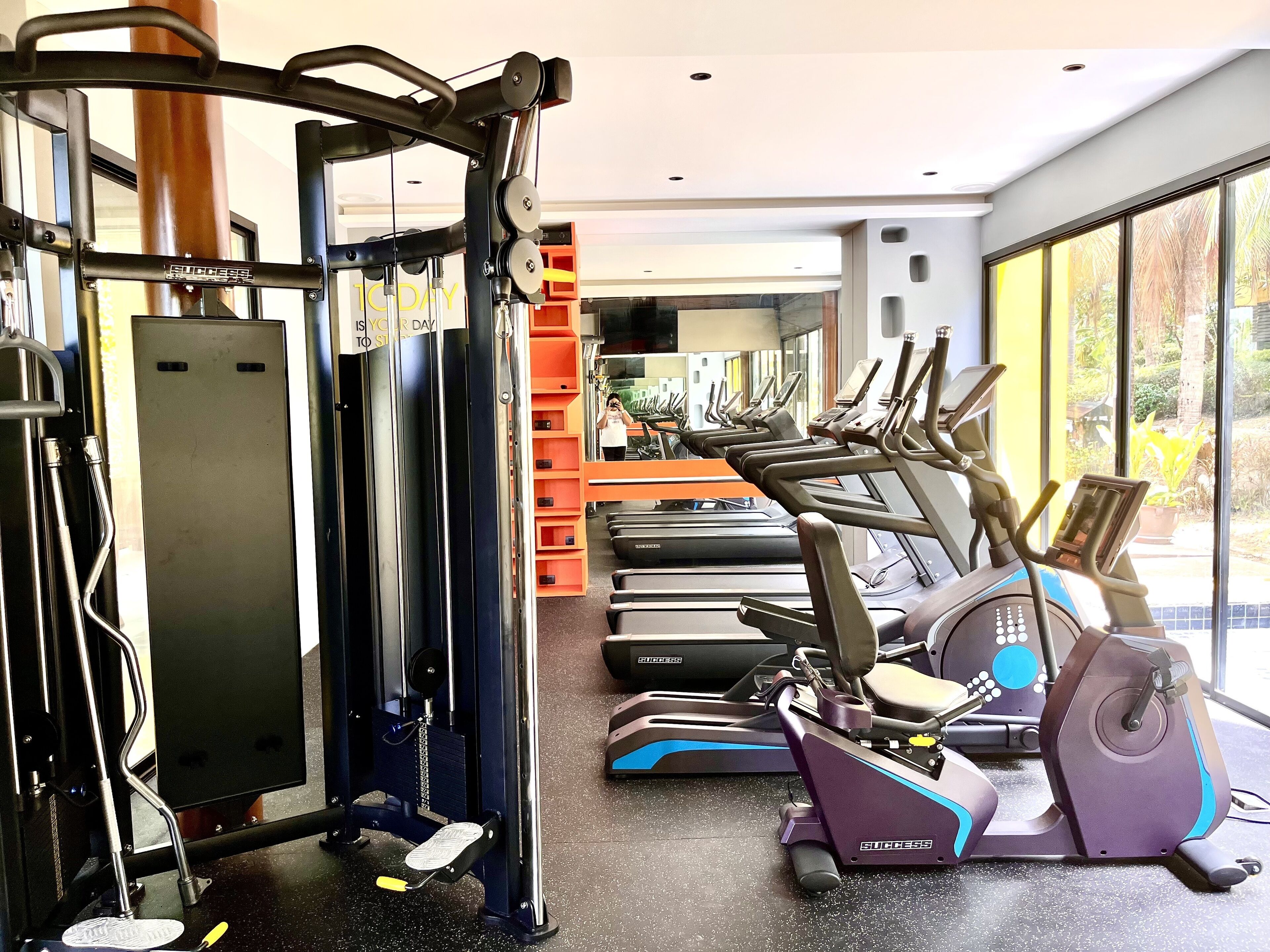 Ein Fitnessstudio mit Trainingsgeräten, darunter Laufbänder und ein Crosstrainer.