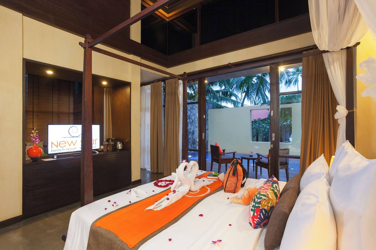 A hotel room with a bed, a desk, and a view of the outdoors.
