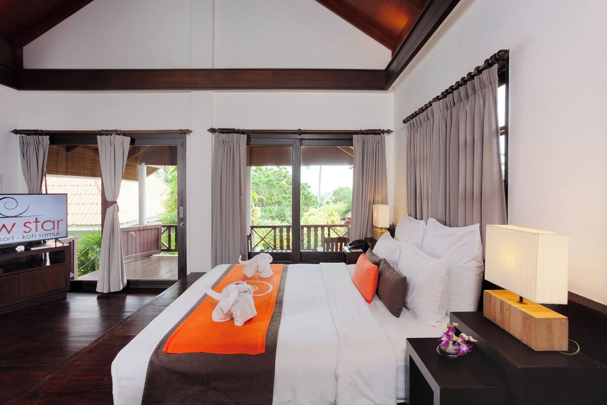 A hotel room with a bed, a TV, a desk, and a view of the outdoors.