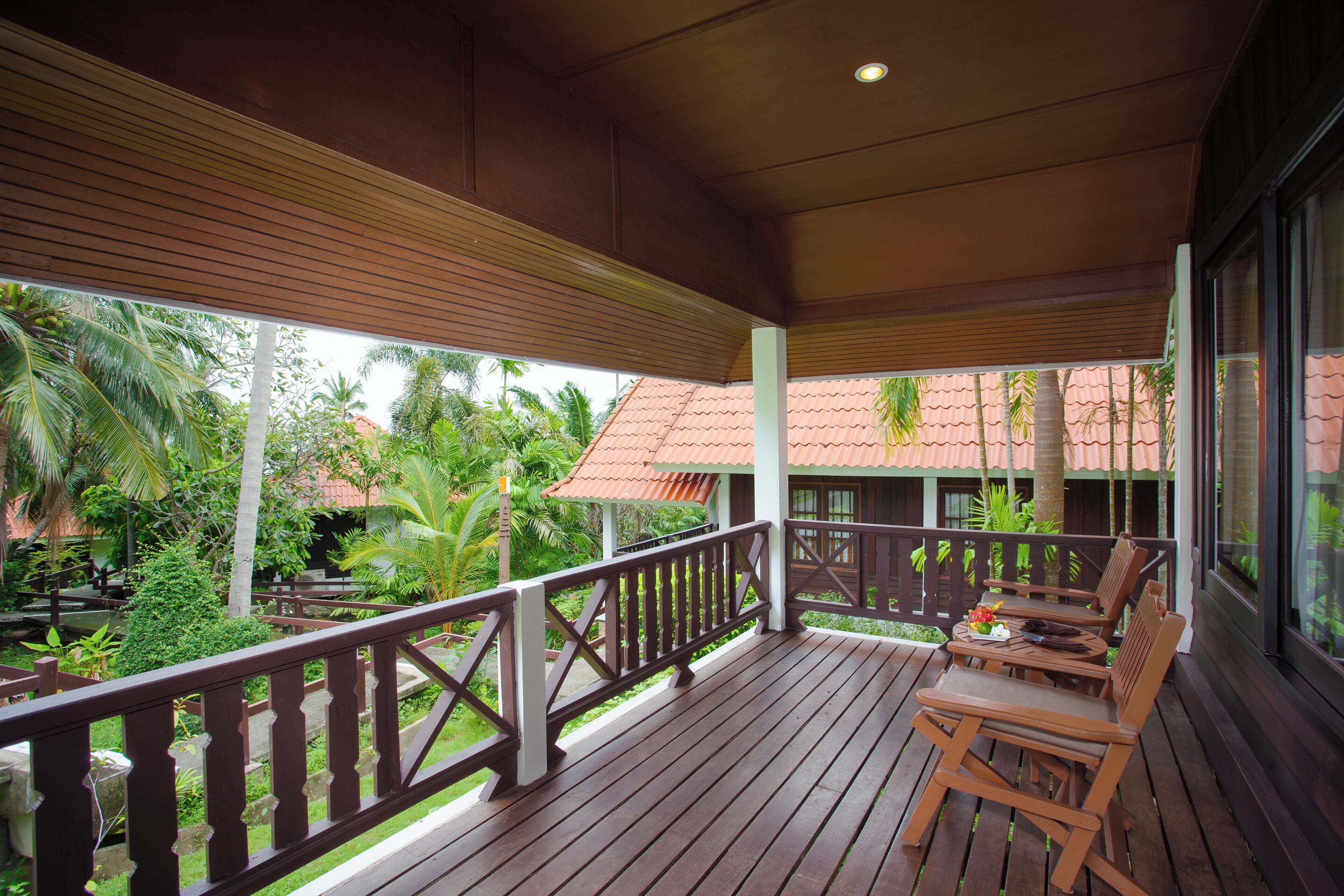 A wooden deck with a railing, tables, and chairs.
