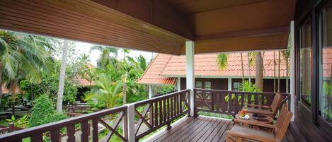 A wooden deck with a railing, tables, and chairs.