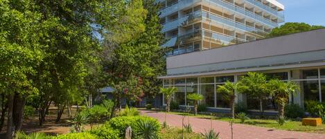 A modern building with a glass facade, surrounded by lush greenery and a paved walkway.
