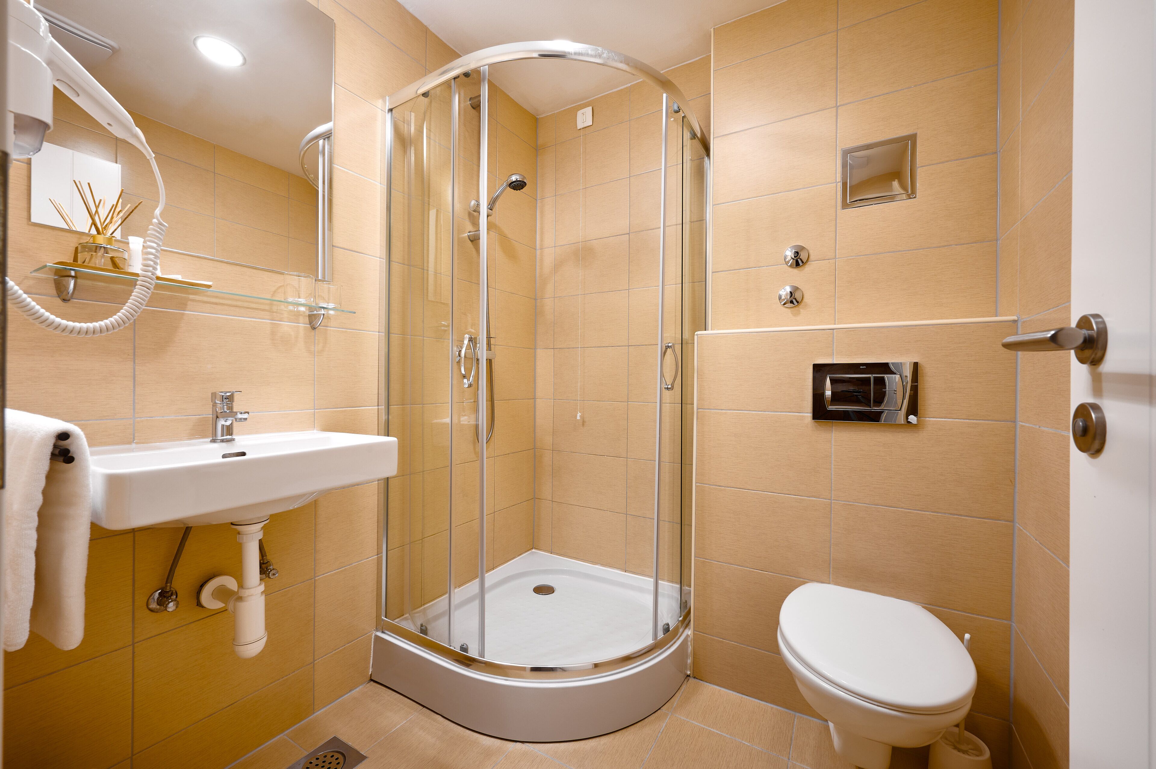 Un baño moderno con ducha de vidrio, lavamanos e inodoro.
