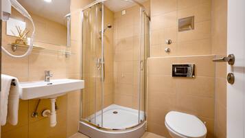 Un baño moderno con ducha de vidrio, lavamanos e inodoro.
