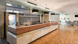 A reception area with a marble floor, wooden reception desk, and a wall of framed photos. - Hotel Imperial Vodice (Vodice)