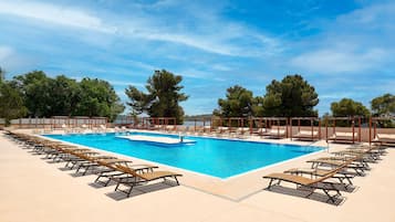 A large outdoor swimming pool with multiple lounge chairs and a clear blue sky.