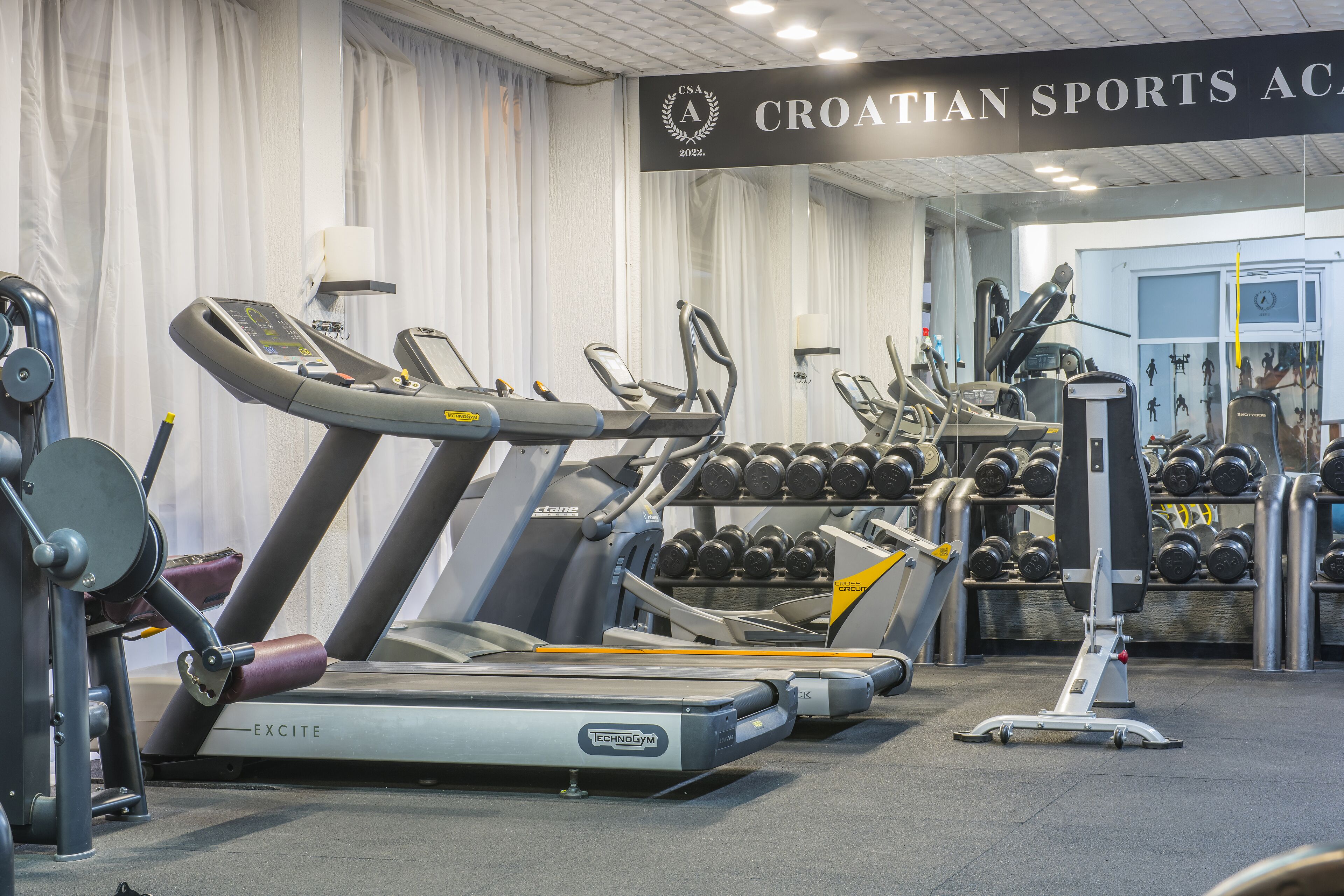 A gym with treadmills, dumbbells, and weight machines.