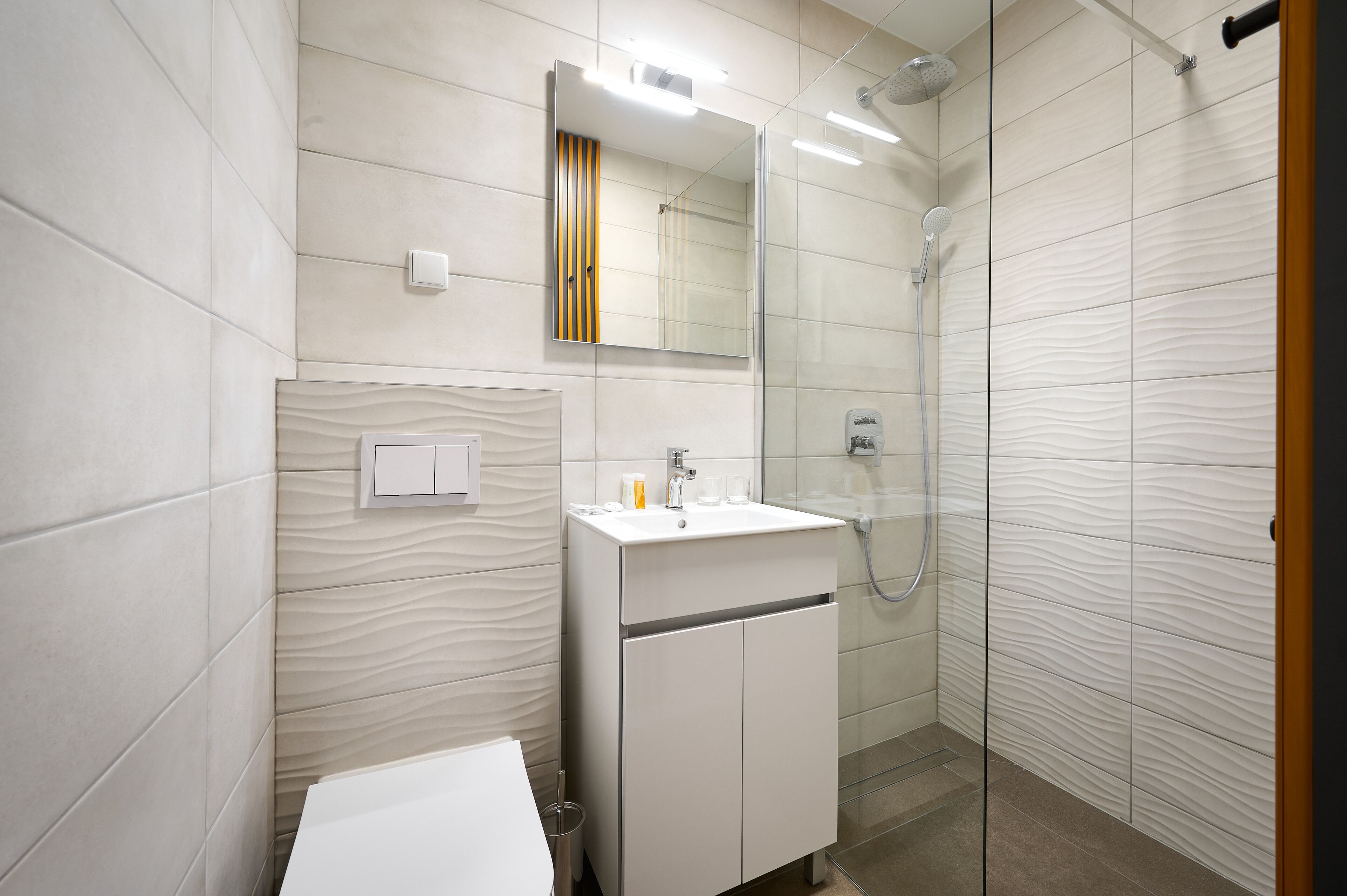 A modern bathroom with a white sink, mirror, and shower.