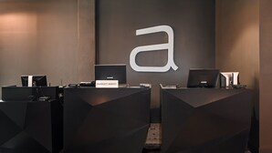 En receptionsdisk med en stor logotyp i form av bokstaven ”a”, flera datorarbetsplatser och belysning i taket.