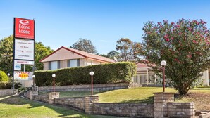 A motel with a signboard, a lawn, a brick wall, and a tree. - Econo Lodge Alabaster (Cowra)
