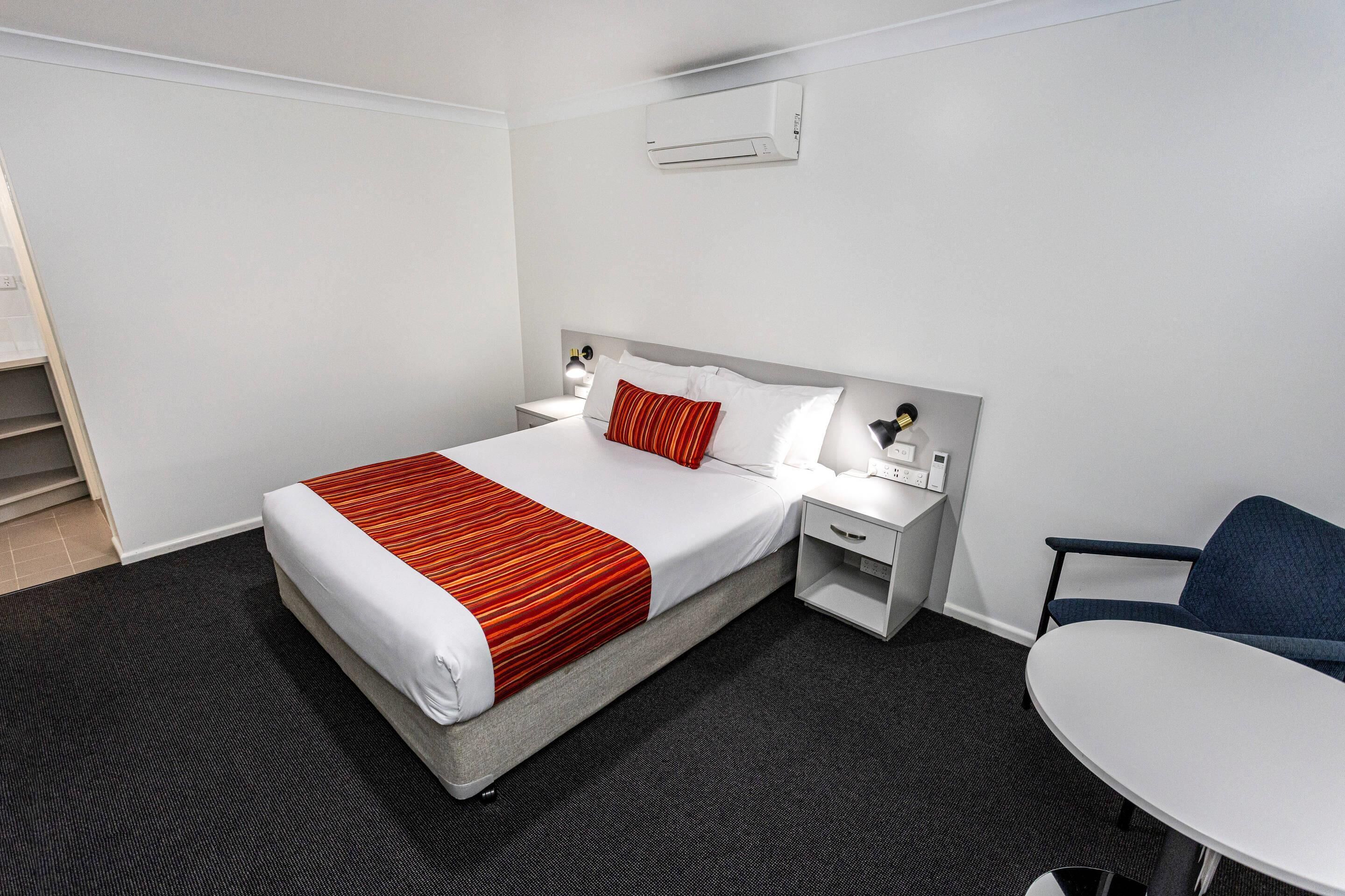 Une chambre d’hôtel avec un lit, des tables de chevet, une chaise et un bureau.