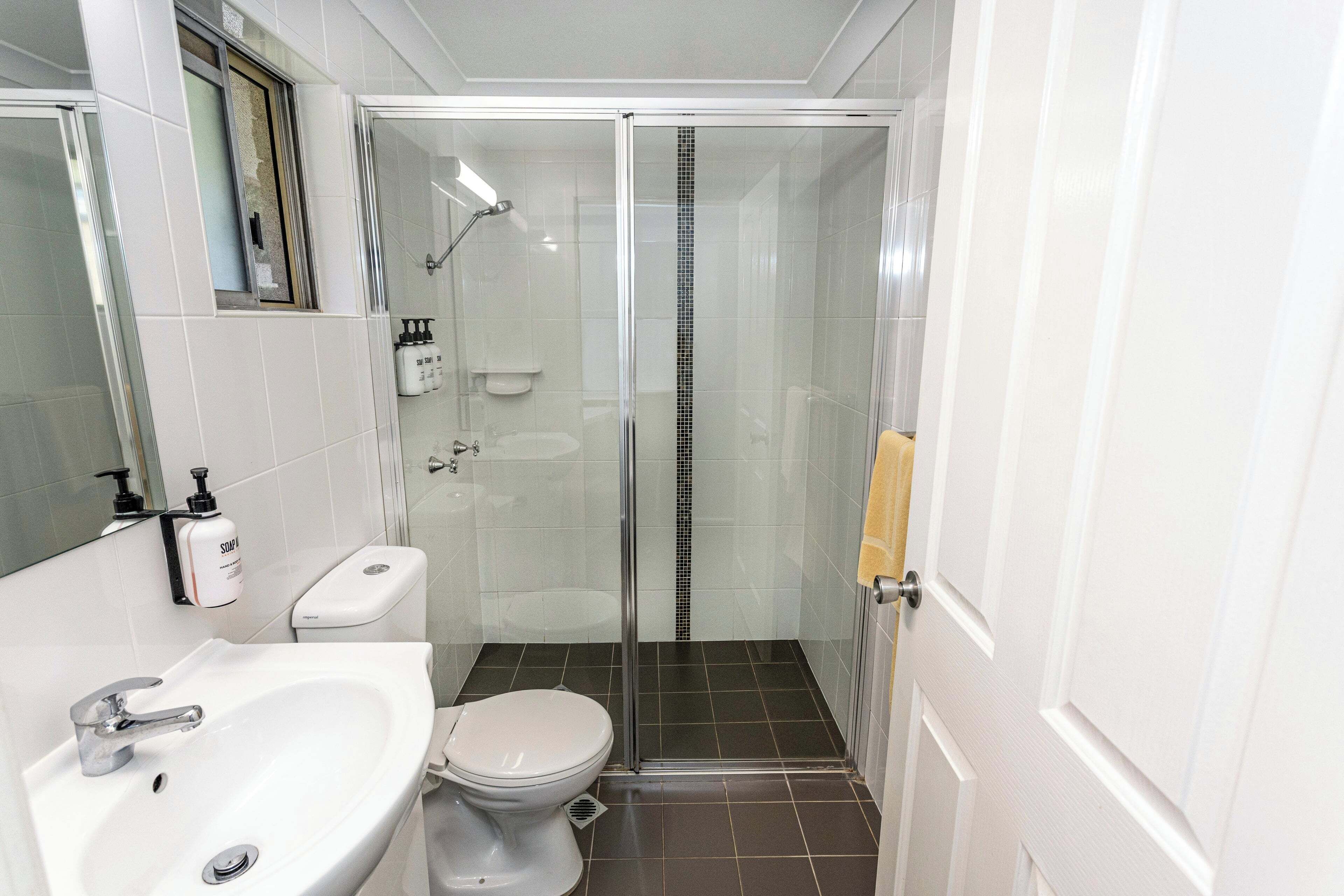 Ein Badezimmer mit weißem Waschbecken, Toilette und einer Duschkabine.