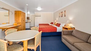 Une chambre d’hôtel comprenant un lit, un canapé, une table à manger avec des chaises, un bureau et un miroir.