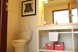 Un bagno con un water, un lavandino con uno specchio sopra e un quadro appeso al muro.