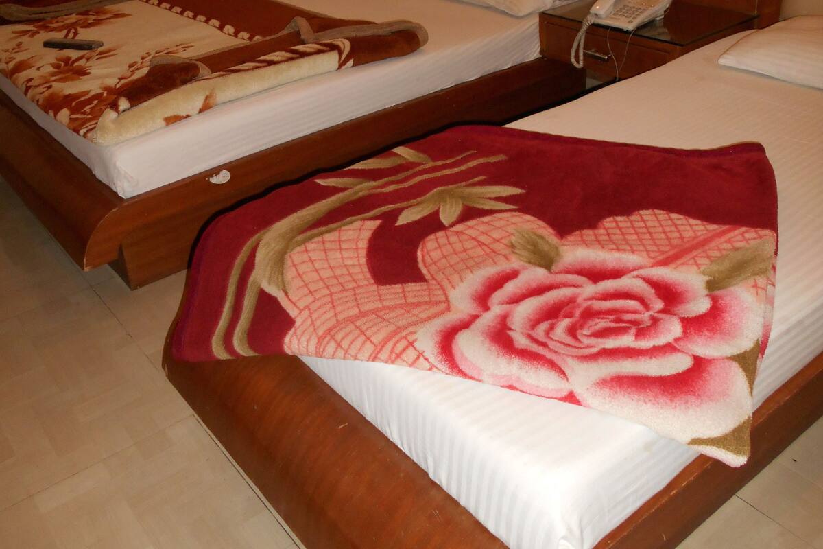 Habitación de hotel con dos camas, cada una con un estilo diferente de ropa de cama. Hay un teléfono en la mesita de noche junto a una cama.