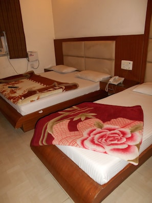 A hotel room with two beds, each with a different style of bedding. There is a telephone on the nightstand next to one bed. - Hotel Pearl Plaza (New Delhi)