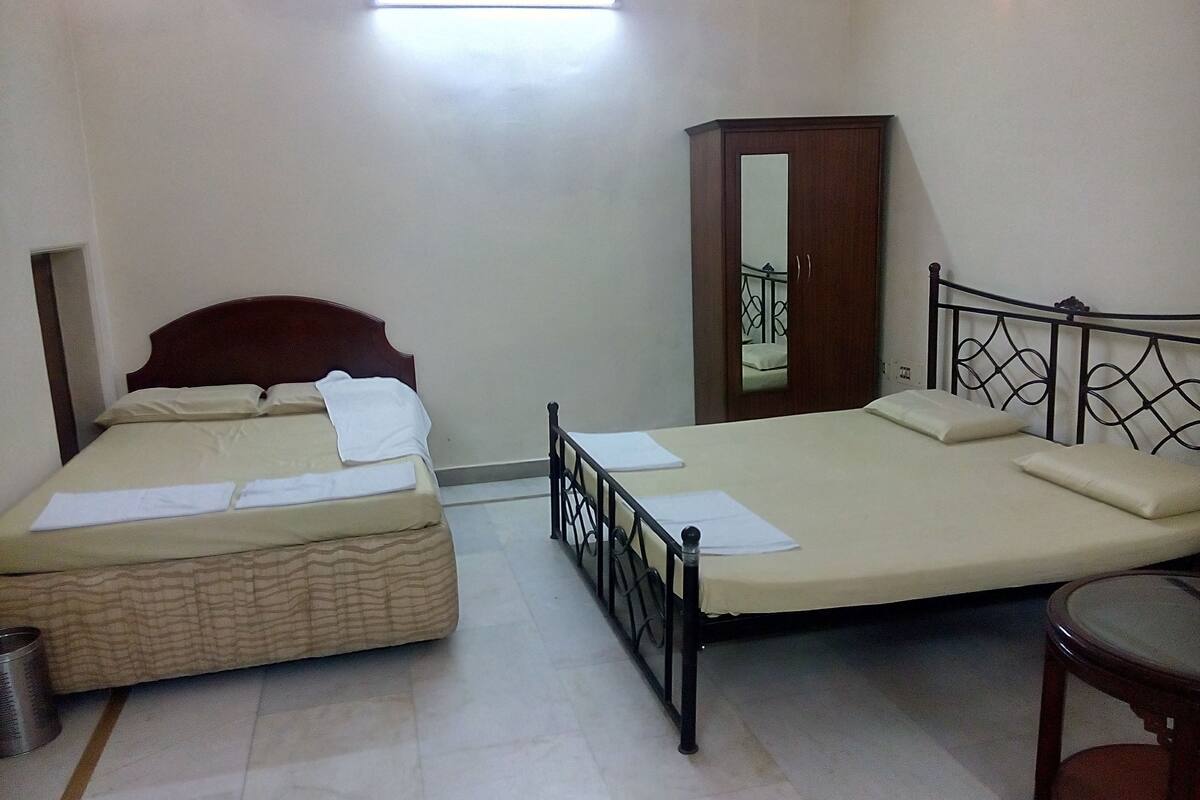 Un dormitorio con dos camas, un armario de madera y una mesita.