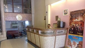 A reception area with a tiled counter, a clock, and a poster advertising live stage shows. - Hotel Pearl Plaza (New Delhi)